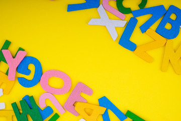 ABC wooden letters alphabet scattered on a yellow background. Education and copy space