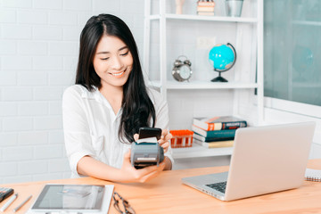 Asian girl holds QR Code on smartphone over credit card machine in supermarket shopping mall...