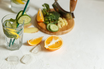 Glass of Sassi water, with ice close-up on a white background with the ingredients for the drink blurry