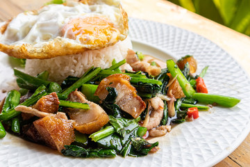Crispy pork with Chinese kale with steamed rice and fried egg on a white plate.