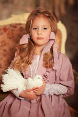 Girl in a pink dress with a white dove in her arms