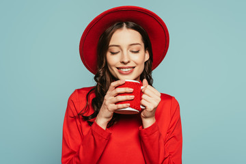 happy stylish girl enjoying flavor of coffee with closed eyes isolated on blue