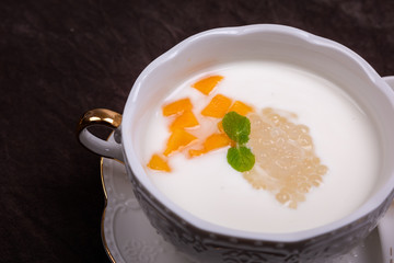 Sweet soup in a white cup against a dark background