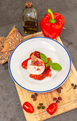 Burrata served at an Italian restaurant with red pepper and topped with basil