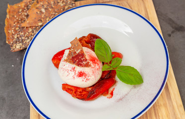 Burrata served at an Italian restaurant with red pepper and topped with basil