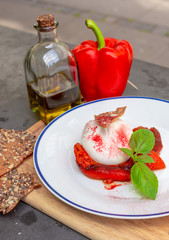 Burrata served at an Italian restaurant with red pepper and topped with basil