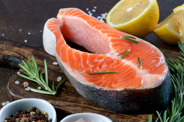 salmon steak on a dark background with lemon and spices