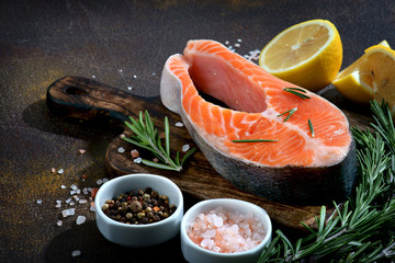salmon steak on a dark background with lemon and spices