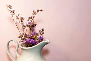 Purple flowers in a white vase on a pink background with copy space. Greeting card, banner. invitation. Women's Day, Mother's Day