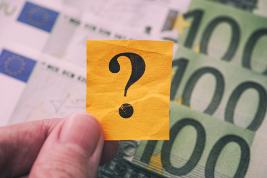 Person holds yellow paper note with question mark in his hand against Euro banknotes background