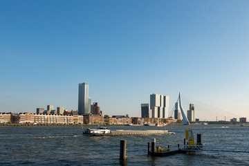 Skyline of Rotterdam over the Maas river with a boat in the Netherlands
