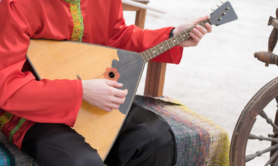 the musician plays a Russian folk musical instrument, a balalaika, in an ancient national costume