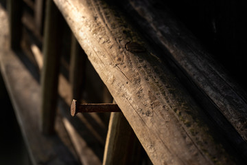 Closeup of wooden ladder hanging on rusty nail in barn