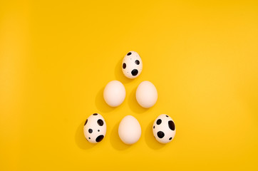 Obraz premium Many White eggs with green myrtle leaves pattern on yellow color background. Spring and Easter holiday concept with copy space.