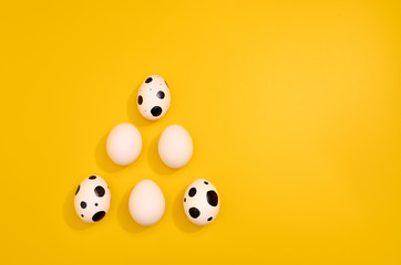 Many White eggs with green myrtle leaves pattern on yellow color background. Spring and Easter holiday concept with copy space.
