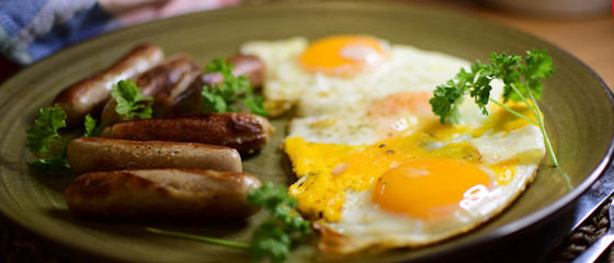 Fried Bavarian sausages and fried eggs are served on a ceramic plate.