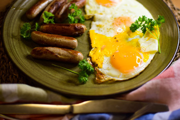 Fried Bavarian sausages and fried eggs are served on a ceramic plate.