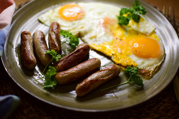 Fried Bavarian sausages and fried eggs are served on a ceramic plate.