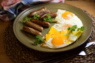Fried Bavarian sausages and fried eggs are served on a ceramic plate.