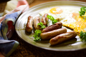 Fried Bavarian sausages and fried eggs are served on a ceramic plate.