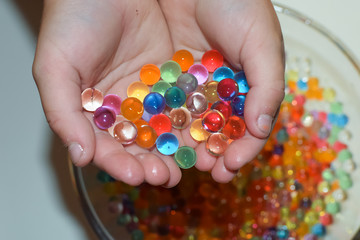 The child plays with multi-colored hydrogel balls.