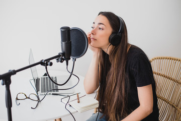 Woman blogger recording radio podcast in studio.