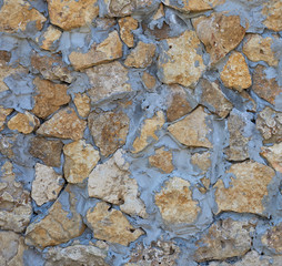 wall of yellow stones of different sizes fastened with gray cement