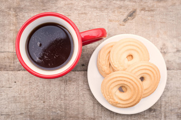 Dark tea in a red polka dot mug with biscuit