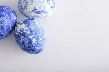three classic blue Easter eggs with gradient effect in corner on white background