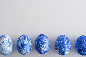 top view five Easter eggs with blue gradient effect in row on white background