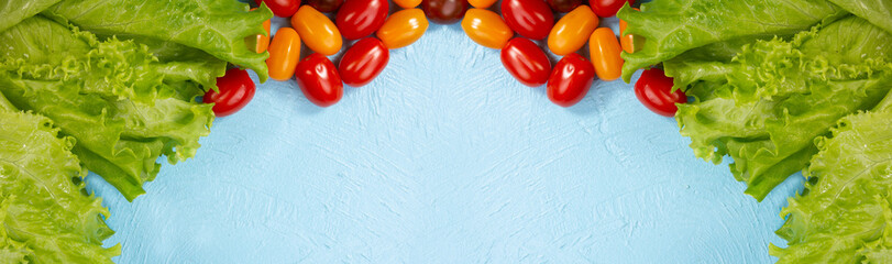 juicy lettuce leaves and ripe cherry tomatoes on a light blue textured background