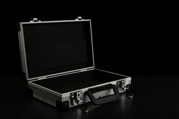 opened empty aluminum suitcase on a black background. stylish aluminum case on a dark background