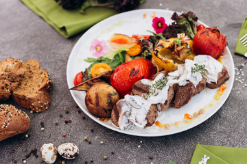 Grilled steak and vegetables on a dish with brown bread. 