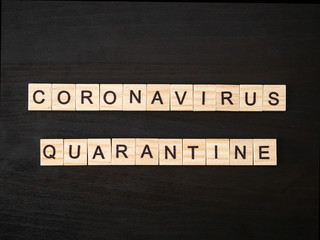 Coronavirus quarantine words made of wood block. Coronavirus quarantine text on dramatic atmosphere black wooden table. Coronavirus concept top view.