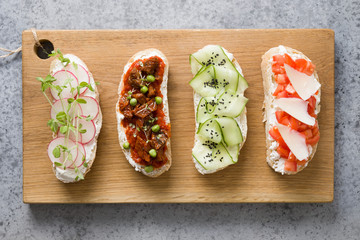 Sandwiches with vegetables, radishes, tomatoes, cucumbers and microgreens on gray. View from above.