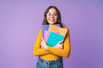 Image of young beautiful student girl smiling and holding exercise books - obrazy, fototapety, plakaty