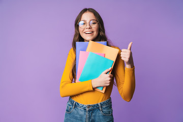 Image of young beautiful student girl smiling and holding exercise books