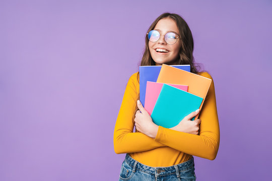 Image of young beautiful student girl smiling and holding exercise books