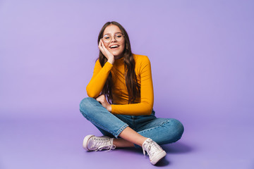 Image of young beautiful woman smiling and sitting with legs crossed