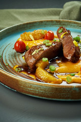 Diet duck breast baked in sauce with carrot puree and tomatoes in a ceramic plate on a wooden background. Selective focus, close up, vertical