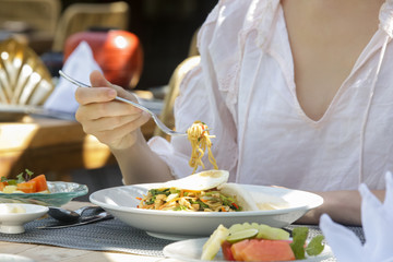 Obraz na płótnie Canvas Woman eating noodle, summertime lunch break, close up image of woman enjoying healthy meal 