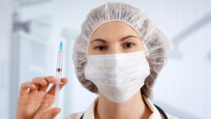 Naklejka premium Professional female doctor in hospital room holding disposable syringe. Woman physician at work