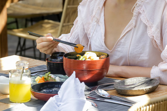 Woman eating traditional Japanese breakfast with chopsticks, summertime lunch break, close up image of woman enjoying healthy meal