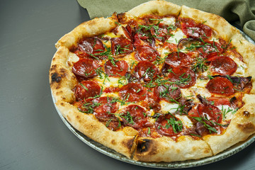 Appetizing pizza with spicy chorizo salami on wooden background in a restaurant. Italian cuisine. Close up, selective focus