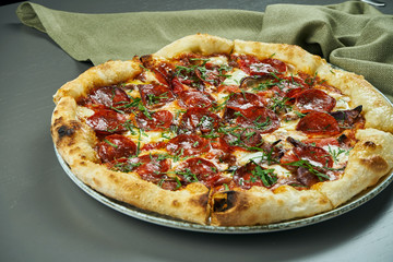 Appetizing pizza with spicy chorizo salami on wooden background in a restaurant. Italian cuisine. Close up, selective focus