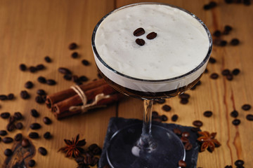 Obraz na płótnie Canvas Espresso martini cocktail in a glass with coffee grains, cinnamon and star anise on a wooden background