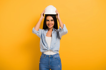 beautiful smiling female manual worker wearing helmet on yellow