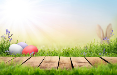 A wooden product display top with an Easter background of painted eggs, rabbit ears, green grass...