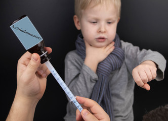 Anti-inflammatory drug for the child. Medicinal syrup in a syringe on the background of a sick boy. The concept of treating children at home.