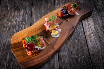 cold cuts of prosciutto with vegetables and eggs on wooden cutting board